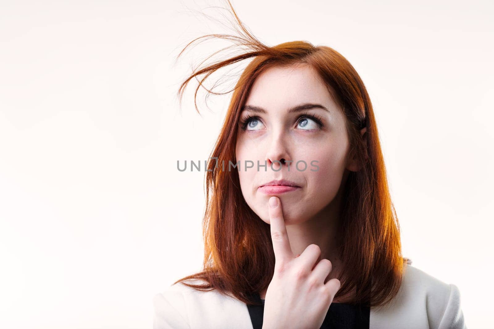 businesswomans upward gaze and finger on chin portray her engagement in thoughtful deliberation