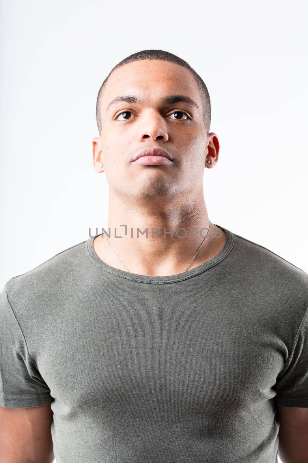 Black man in military pose, looking upward. Whether waiting for orders or simply gazing, he stands tall and stern in a military-green tee, muscular and alert