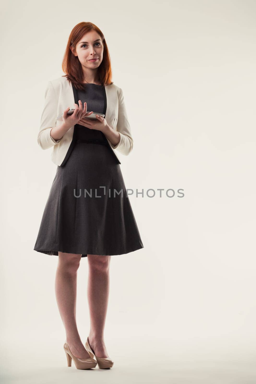 Elegance in the workplace: a professional woman stands with her smartphone, embodying grace and connectivity