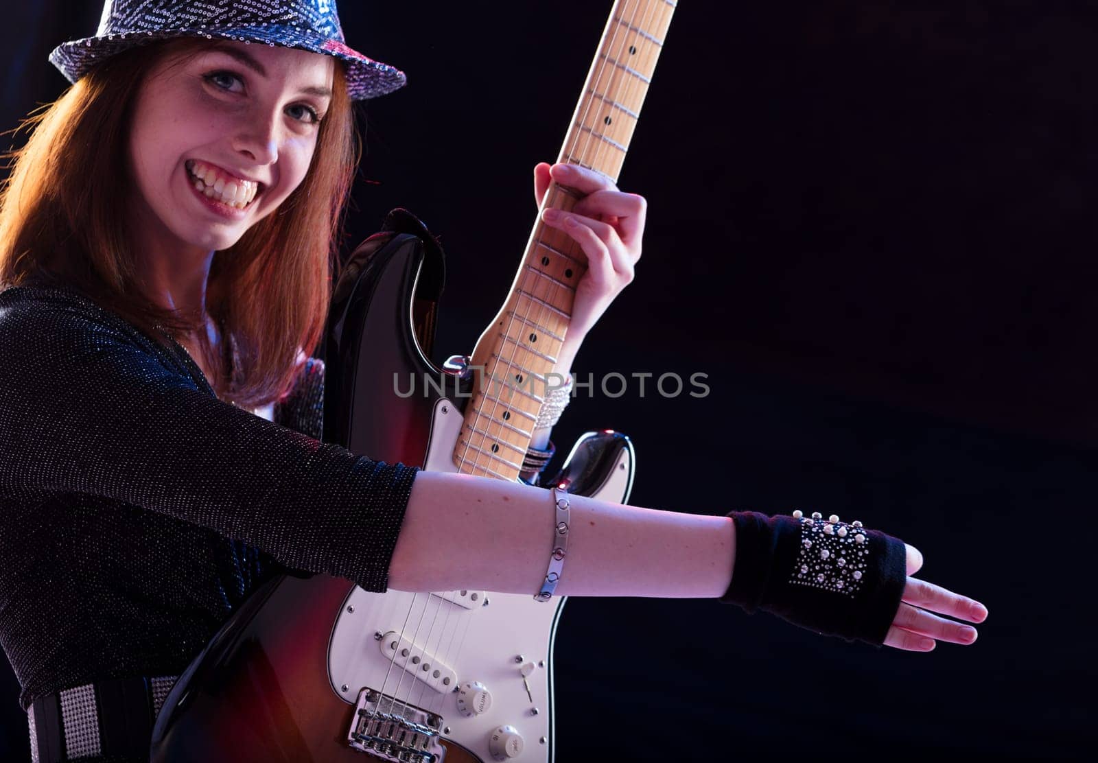 Strumming her guitar, the joyful artist combines her passion for music with a keen sense of style
