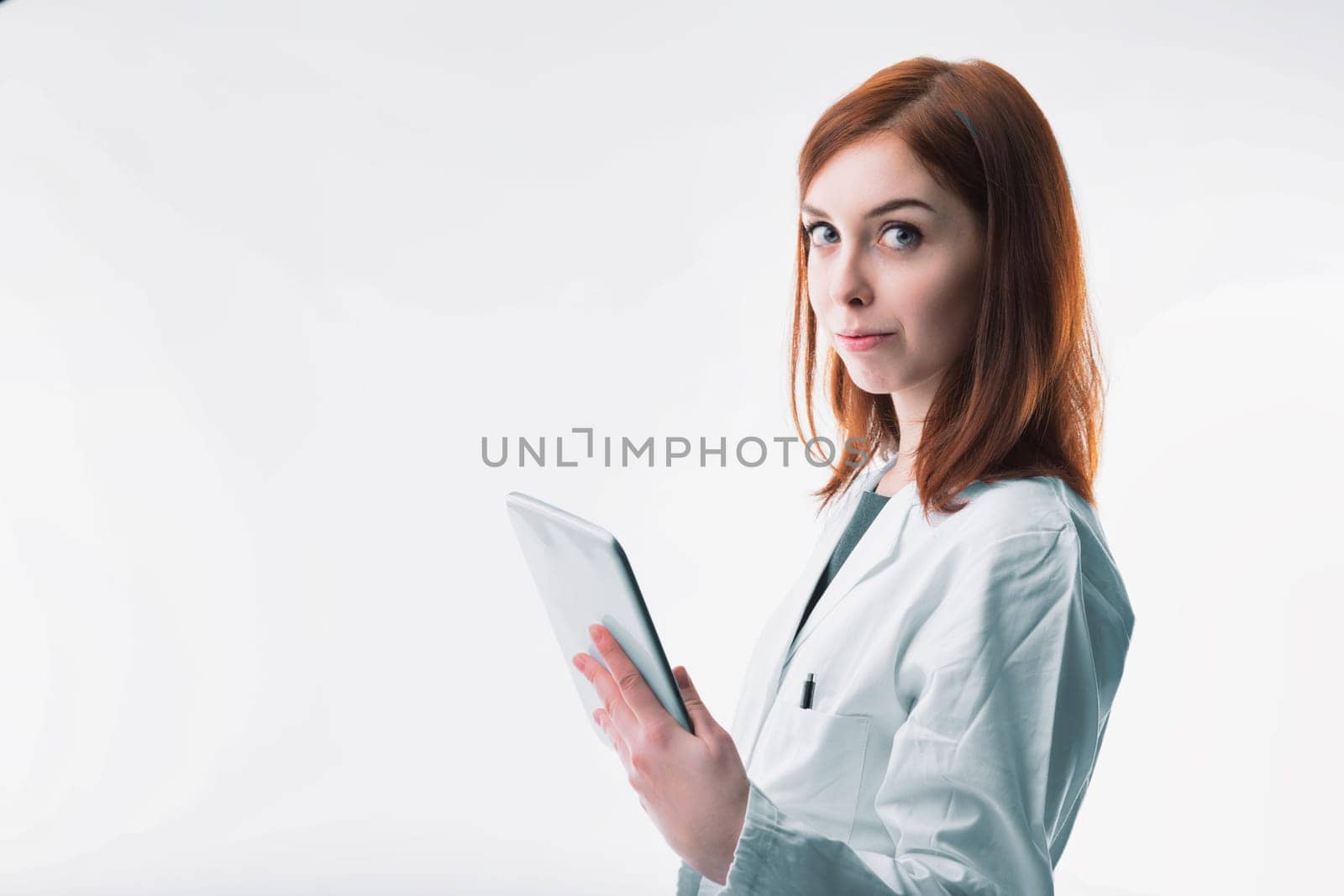 healthcare professional with auburn hair confidently holds a tablet, symbolizing the integration of technology in medicine