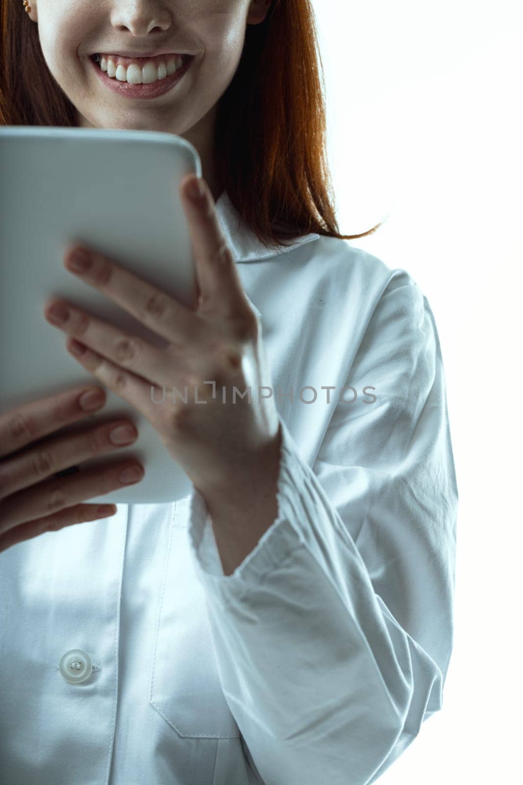 woman's vibrant smile peeks from behind a tablet, hinting at the ease and joy technology brings to her professional life