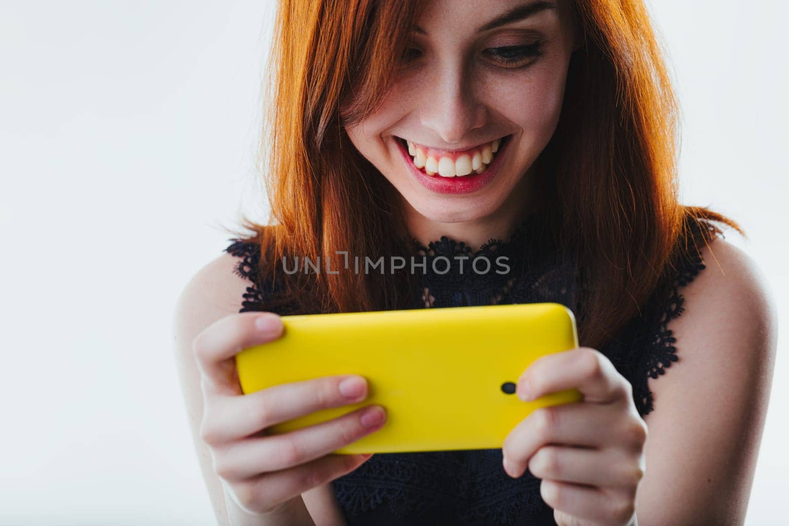 The redheads playful engagement with her mobile device is evident, her eyes alight with the screen's reflection