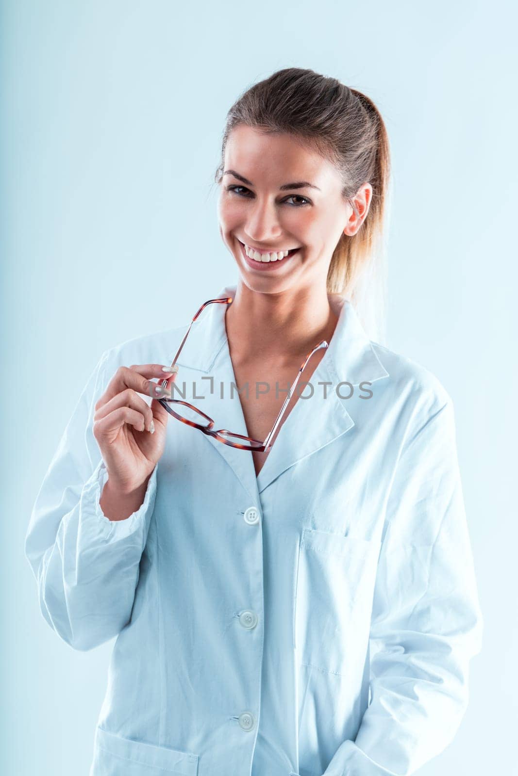 Gentle young woman in white coat with glasses, flashes perfect teeth. An adept professional in science and technology, holding many degrees, her congeniality is serendipitous