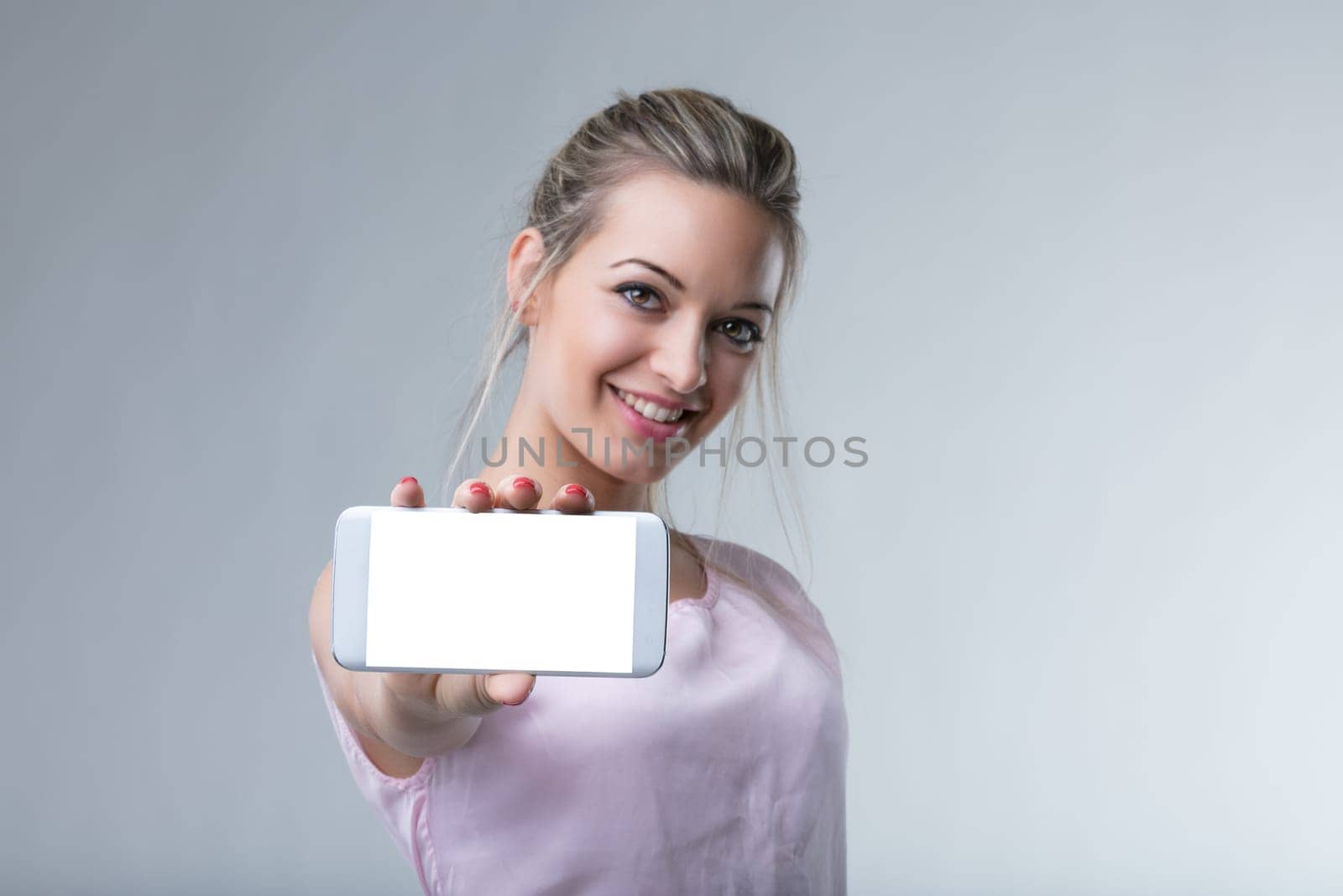 Smiling woman presents a smartphone, highlighting modern connectivity