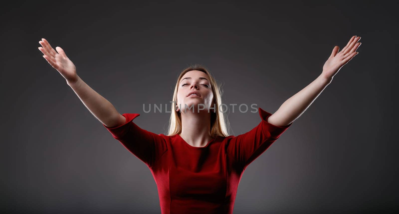 Woman in red raises her arms in a gesture of freedom, eyes closed in serenity
