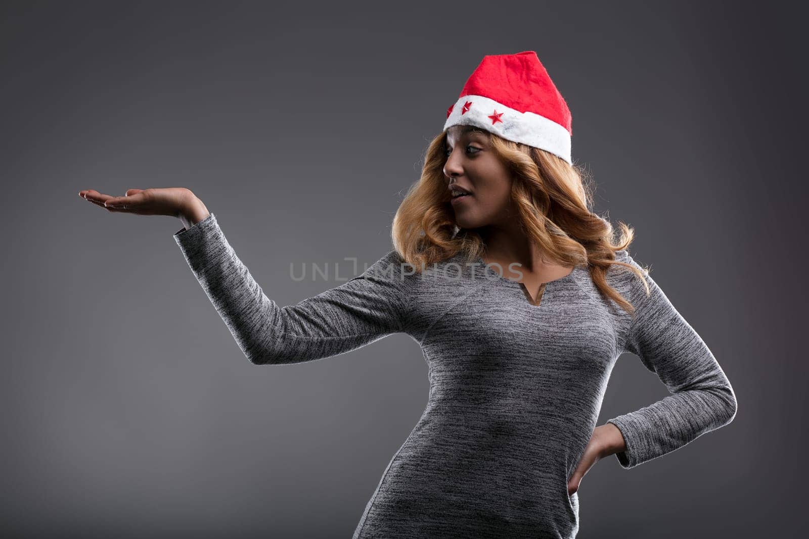 Her exuberant expression under the Santa hat is a burst of holiday excitement as she shows YOUR PRODUCT