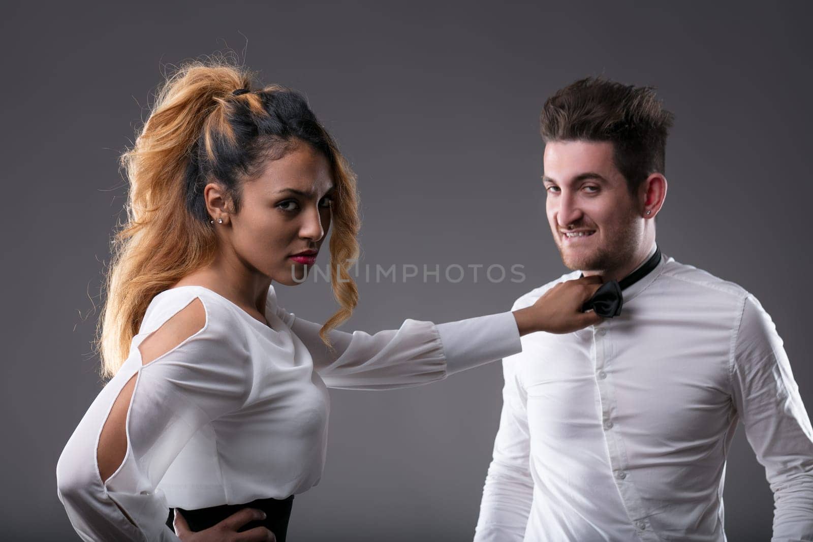 Dominant young black woman firmly holds a man's necktie, her face showing intent to set things right