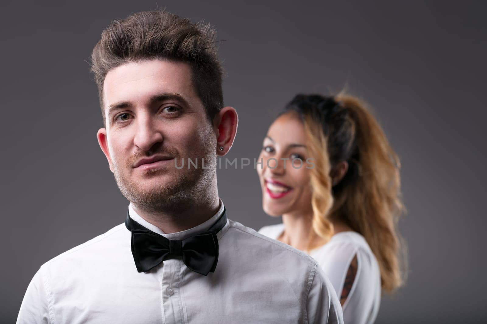 Confident man in foreground, woman's joyful face in the back, both smartly dressed