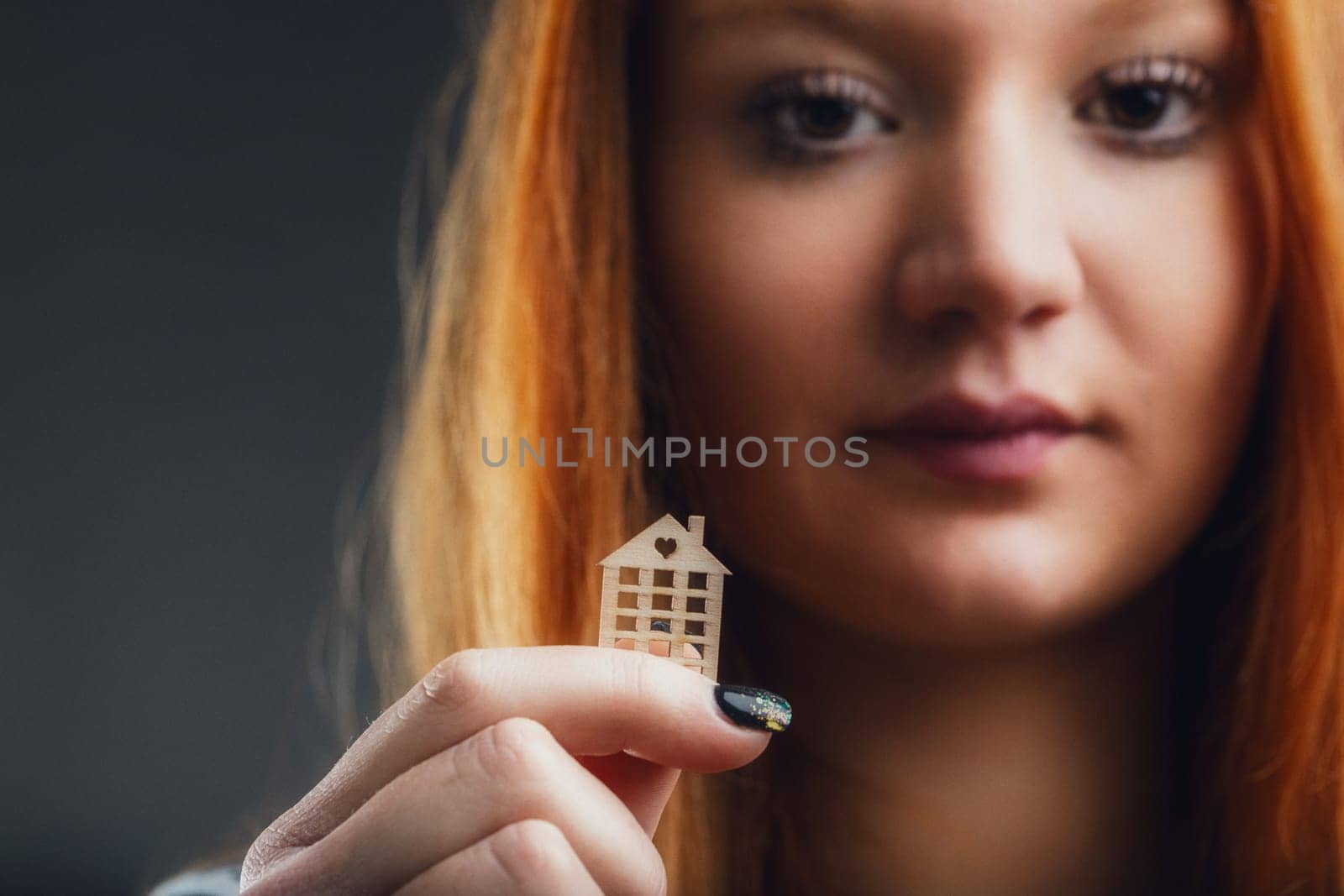 Red-haired woman holds a building-shaped cutout, symbolizing urban living dreams