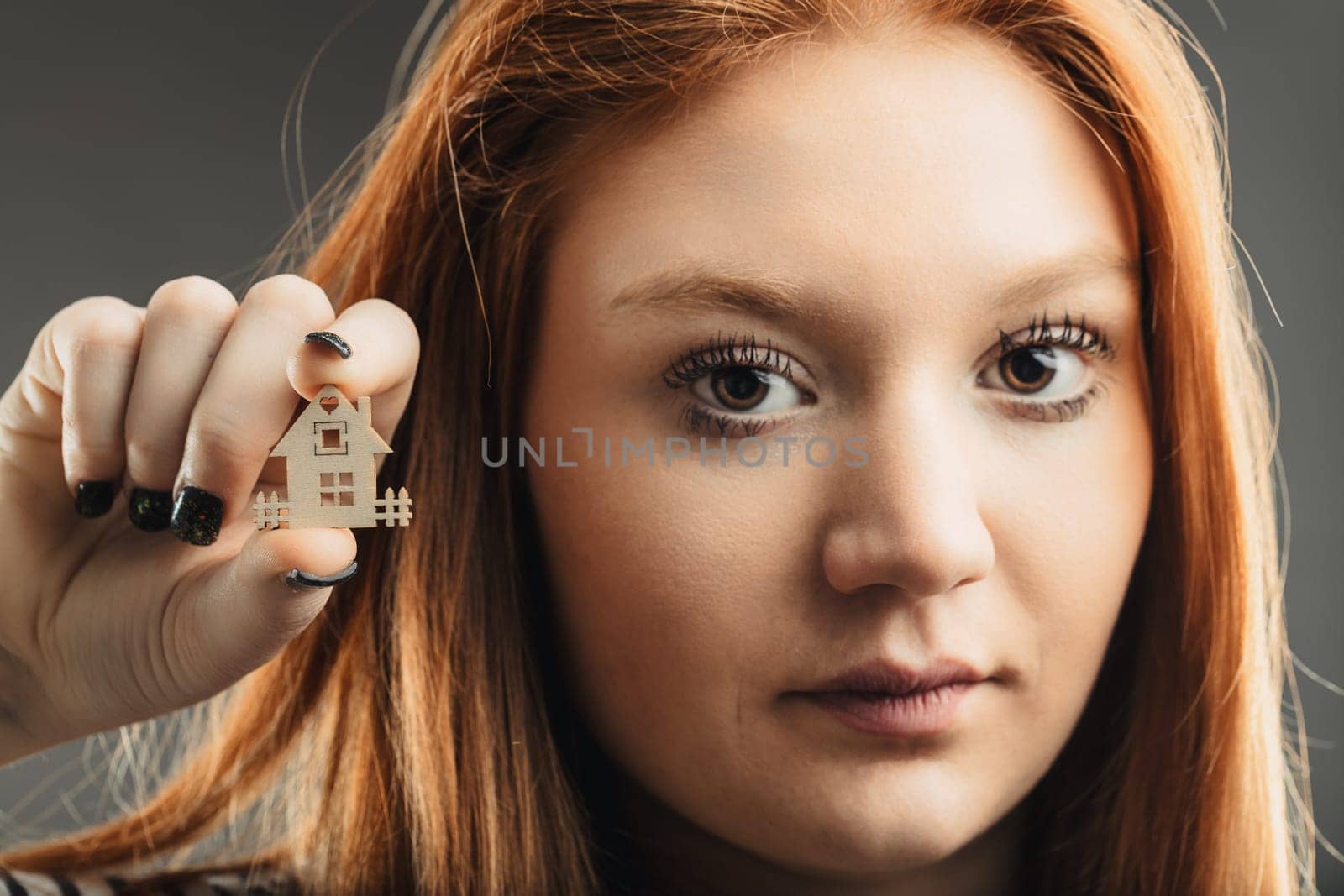 contemplative woman showcases a small home, pondering the concept of shelter