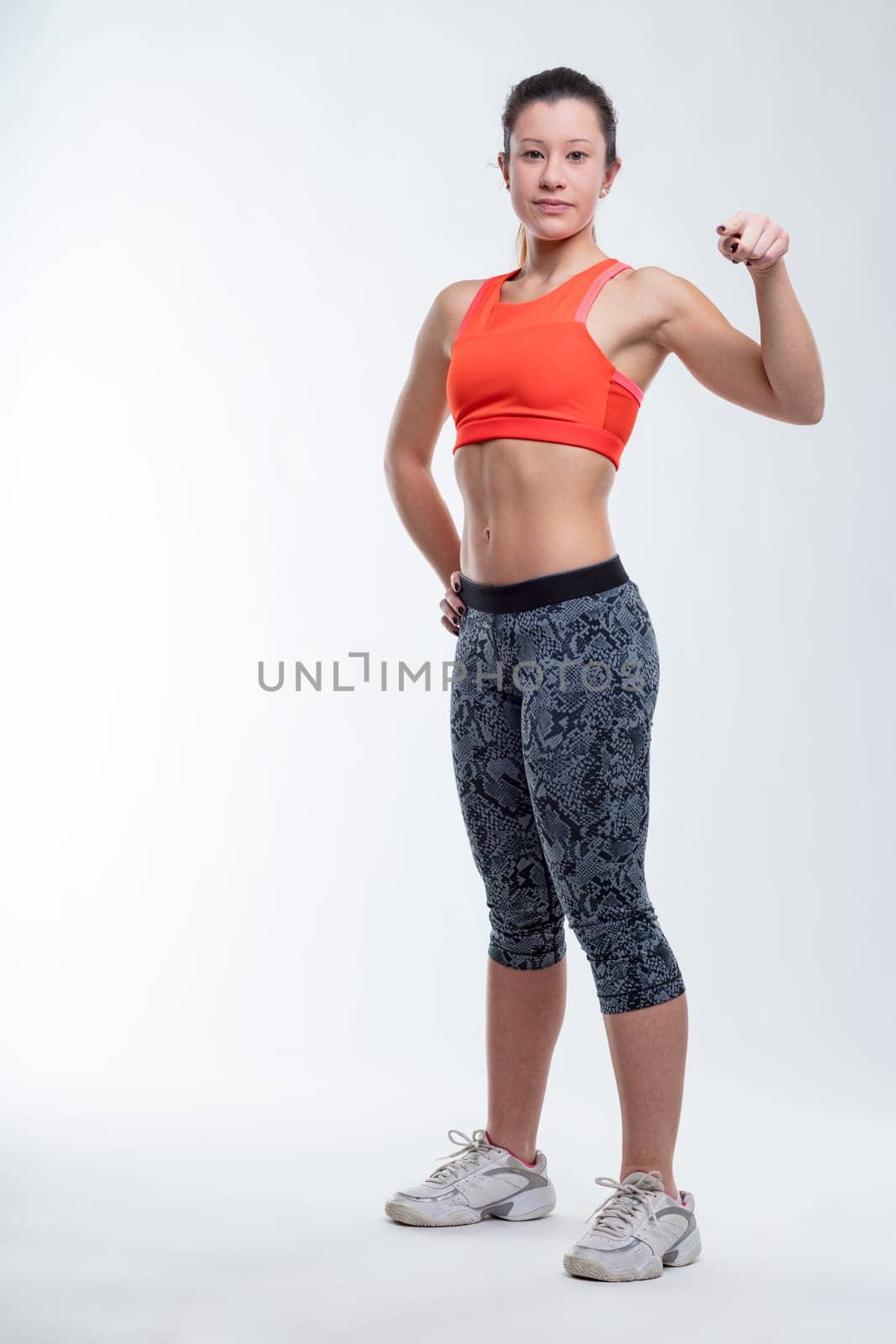 Fitness coach points at you, challenges you to improve. Young, fit, East-Asian woman embodies physical fitness