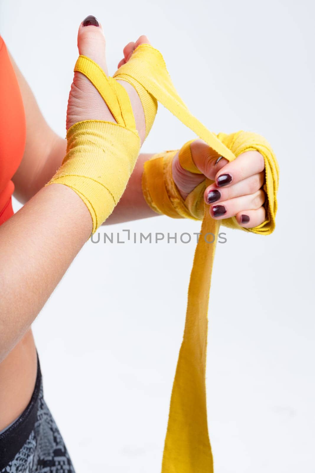 Woman's hands, white background, preparing hand wraps for kick-boxing gloves, promoting fitness and self-assurance