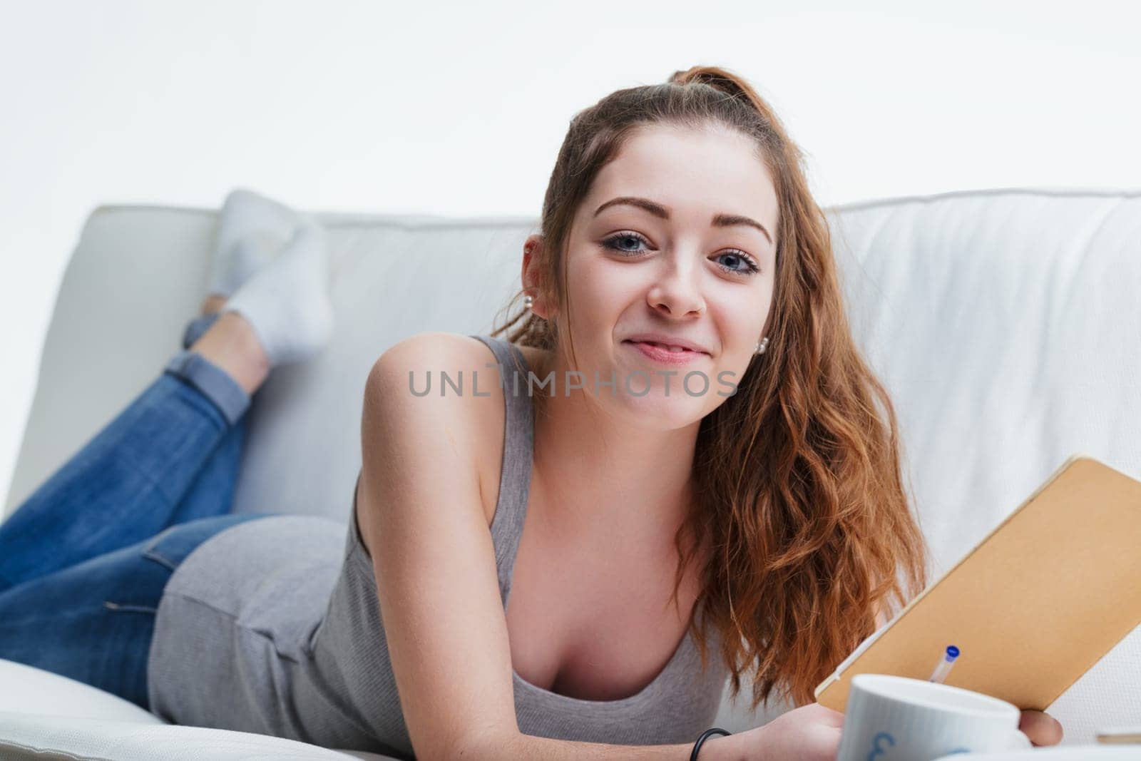 Lounging in comfort, she enjoys a personal moment, perhaps journaling or sketching, in her peaceful living space