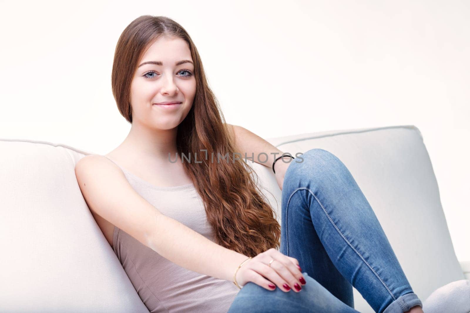 Long brown hair cascades down as the woman sits back, her blue jeans and tank top epitomizing casual comfort