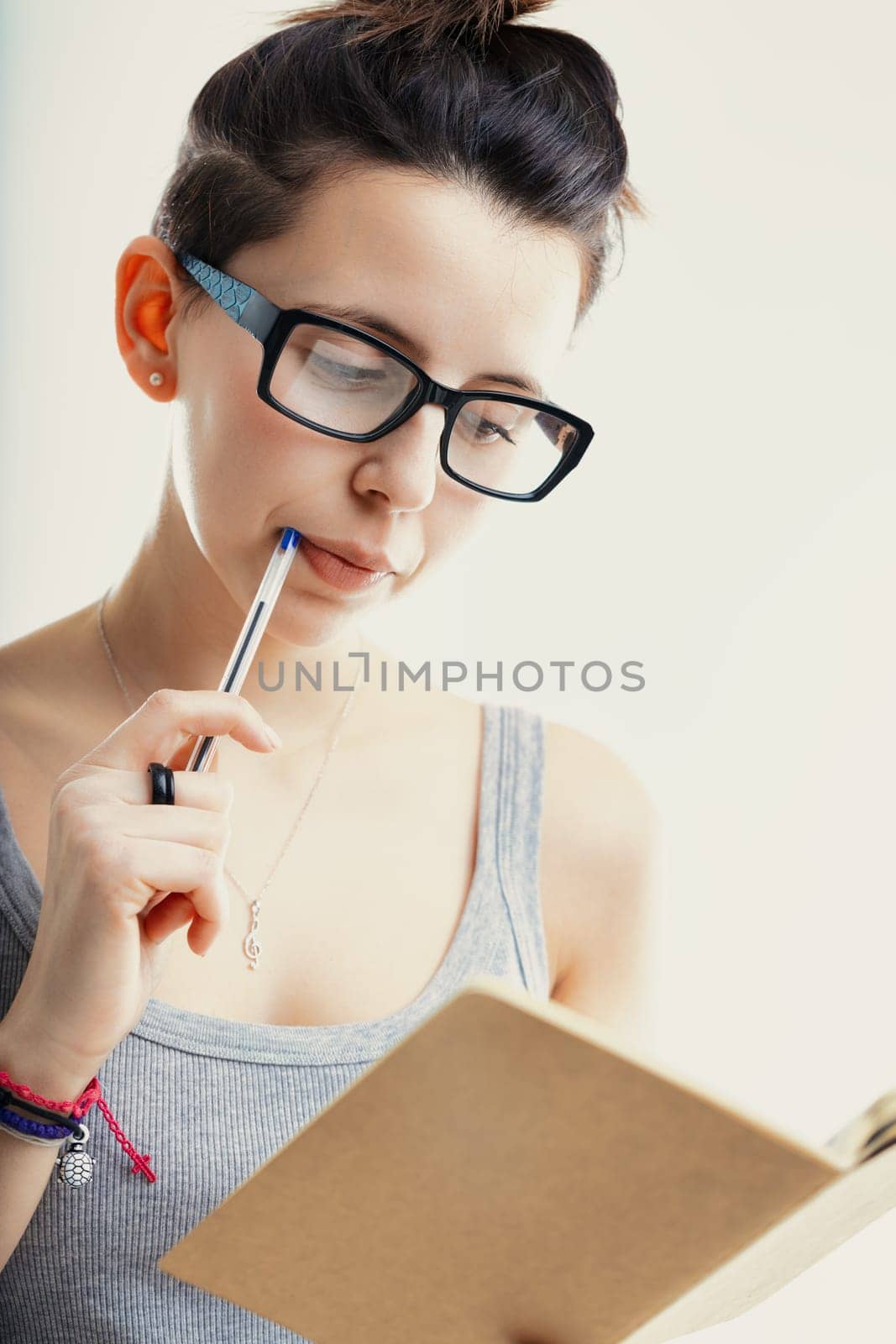 Engrossed in her studies, the woman exhibits focus and concentration, pen in mouth