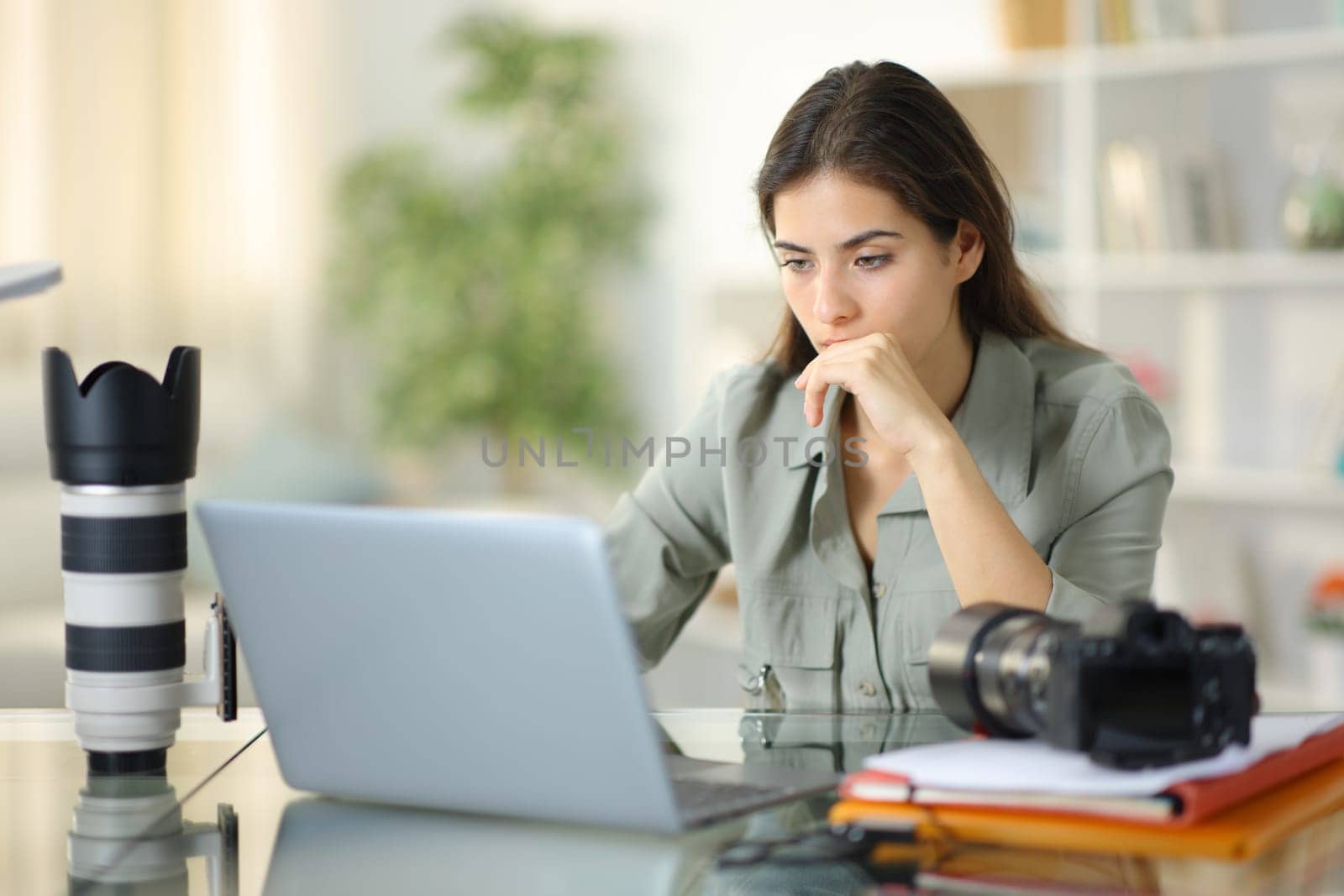 Worried photographer working checking laptop sitting at home