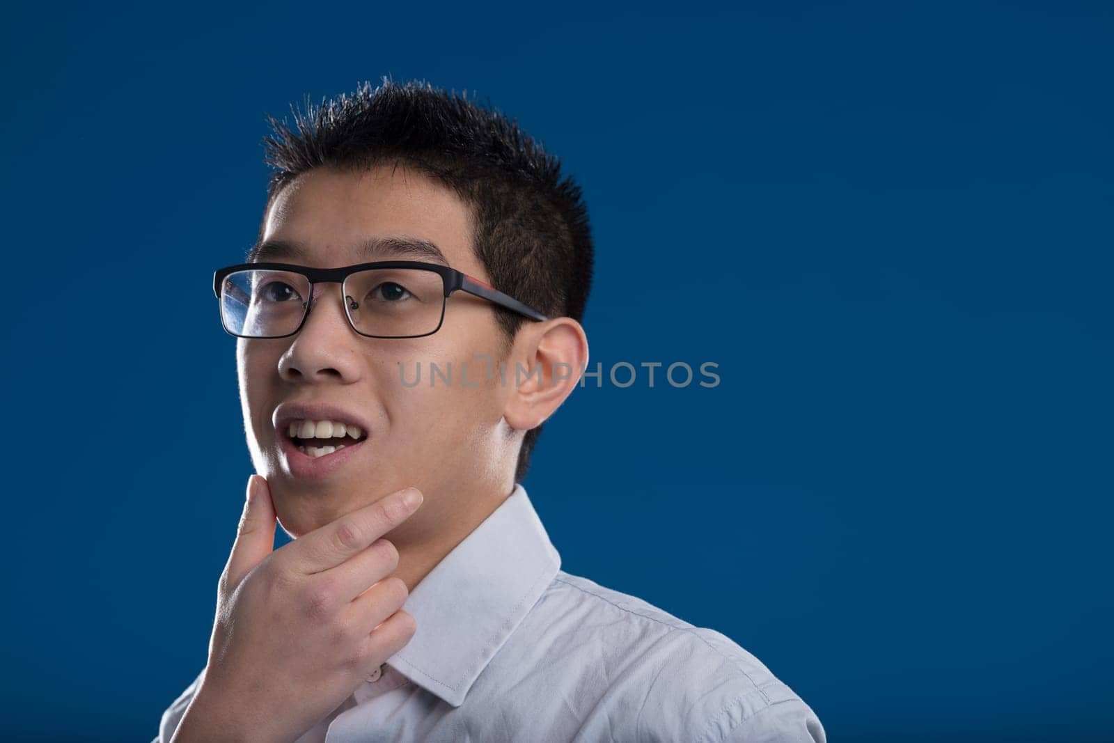 Asian man on a blue background has an idea to solve a problem. His trained mind is about to revolutionize a conventional approach