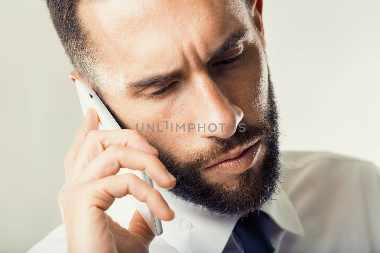 Man in business attire handles a tense call, his intense gaze reflecting the gravity of the conversation