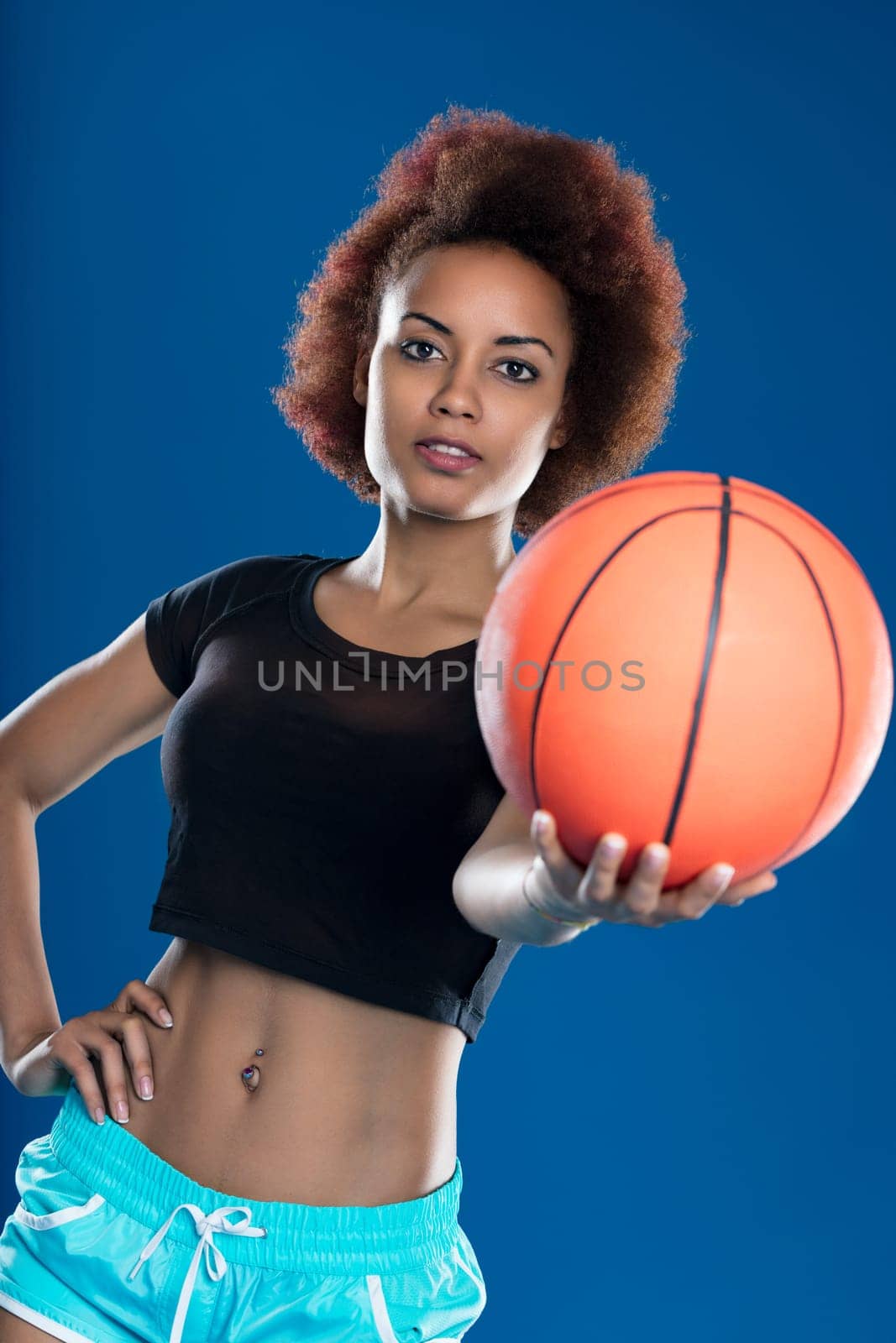 Fitness enthusiast presents a basketball, symbolizing her active and energetic lifestyle