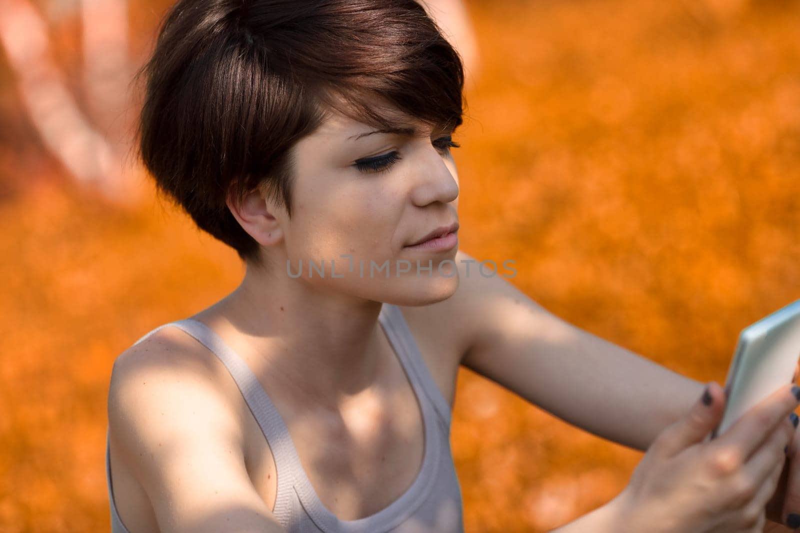 Young woman reading a text message on her mobile phone with a look of serious concentration outdoors in a close up cropped view