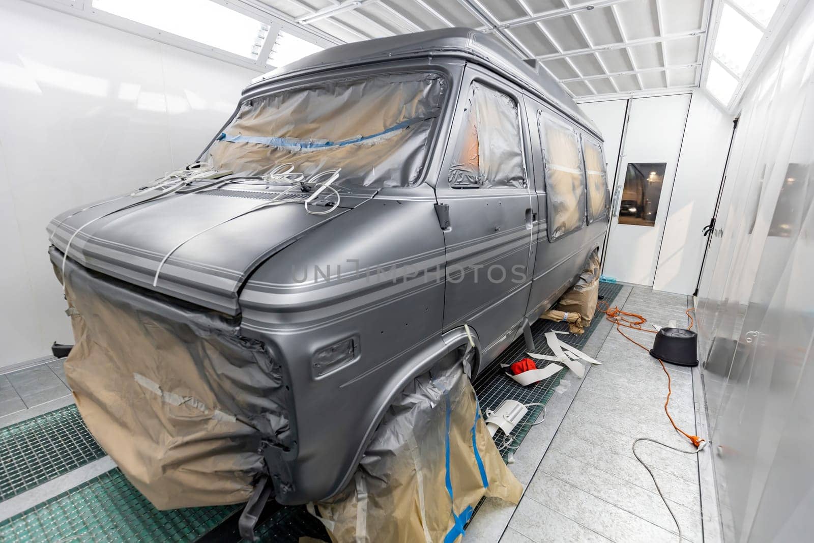 Restoration of a vintage van as it undergoes preparation and receives a gray paint finish inside a thermal spray booth. Meticulous craftsmanship and attention to detail in automotive rehabilitation