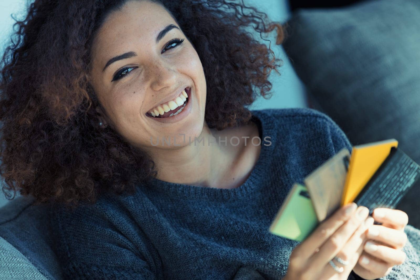 Beautiful curly-haired woman, showcasing perfect teeth and ethnic looks, selects colors from swatches for home decor, intensely absorbed and excited to express her aesthetic preference in her lifestyl