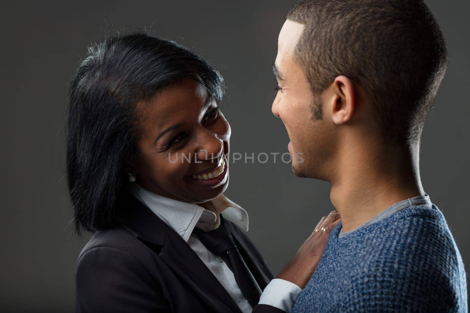 Her professional attire contrasts with his relaxed look, yet their jovial connection bridges any divide