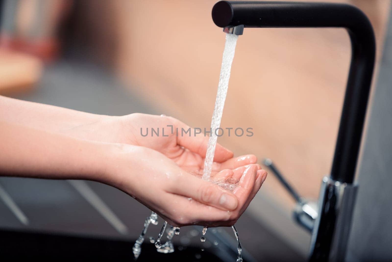 Hands under running water in a kitchen. A detail emphasizing the ease of having pure water, which some value and pay taxes to enjoy