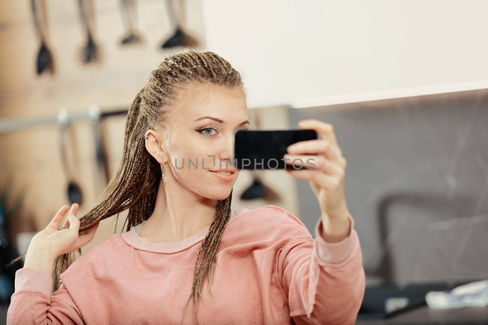 Woman with box-braids enjoys smartphone & laptop in kitchen for work, study, & leisure. Social media's ease has drawbacks
