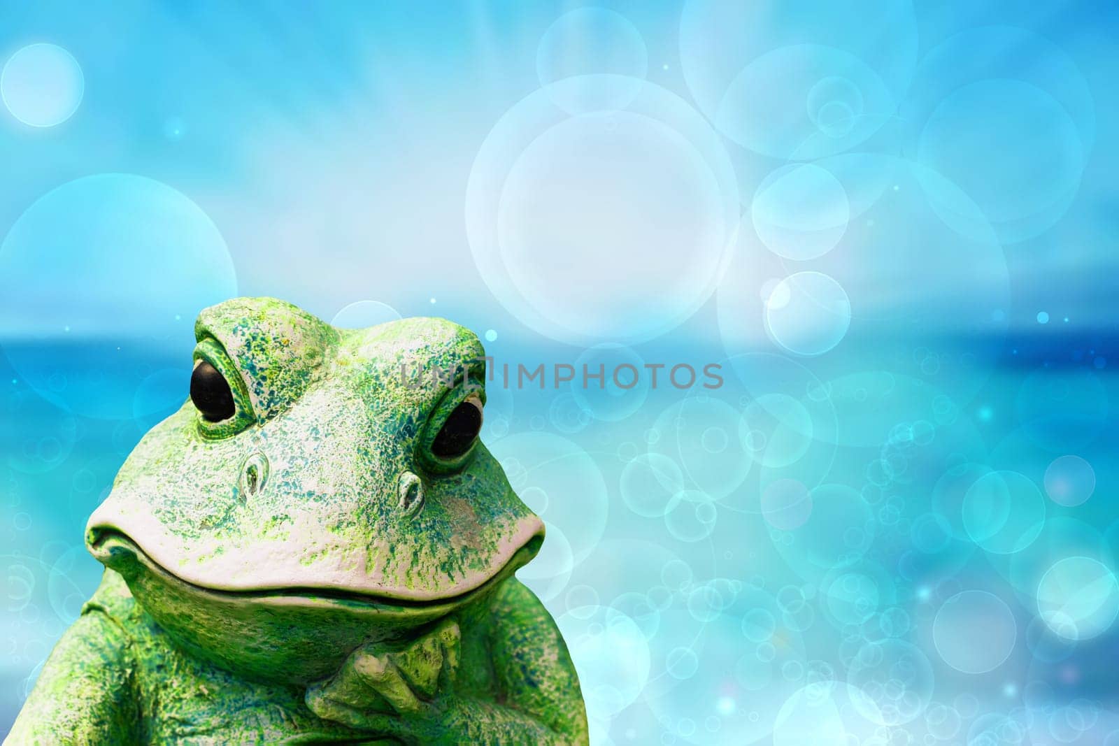 Frog background. Decorative old weathered ceramic frog figure over abstract blue turquoise ocean. Beautiful backdrop for summer holidays and travel advertising.