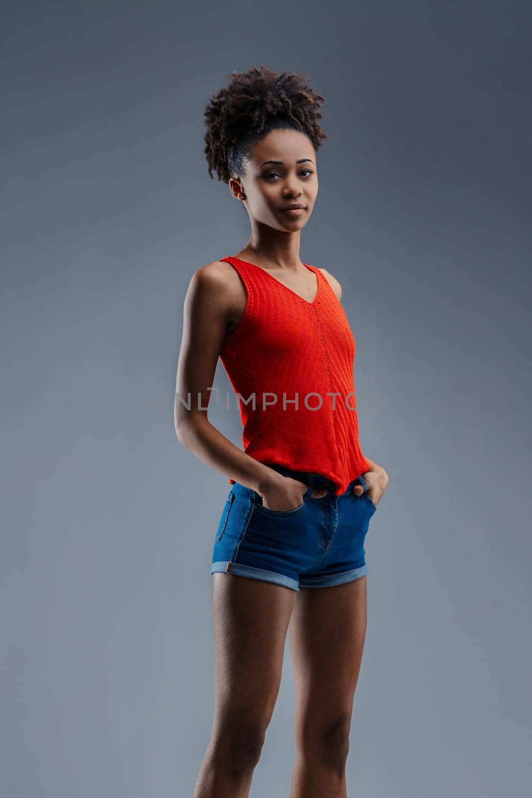 Relaxed yet assertive, a young Black female individual stands tall in a vibrant top