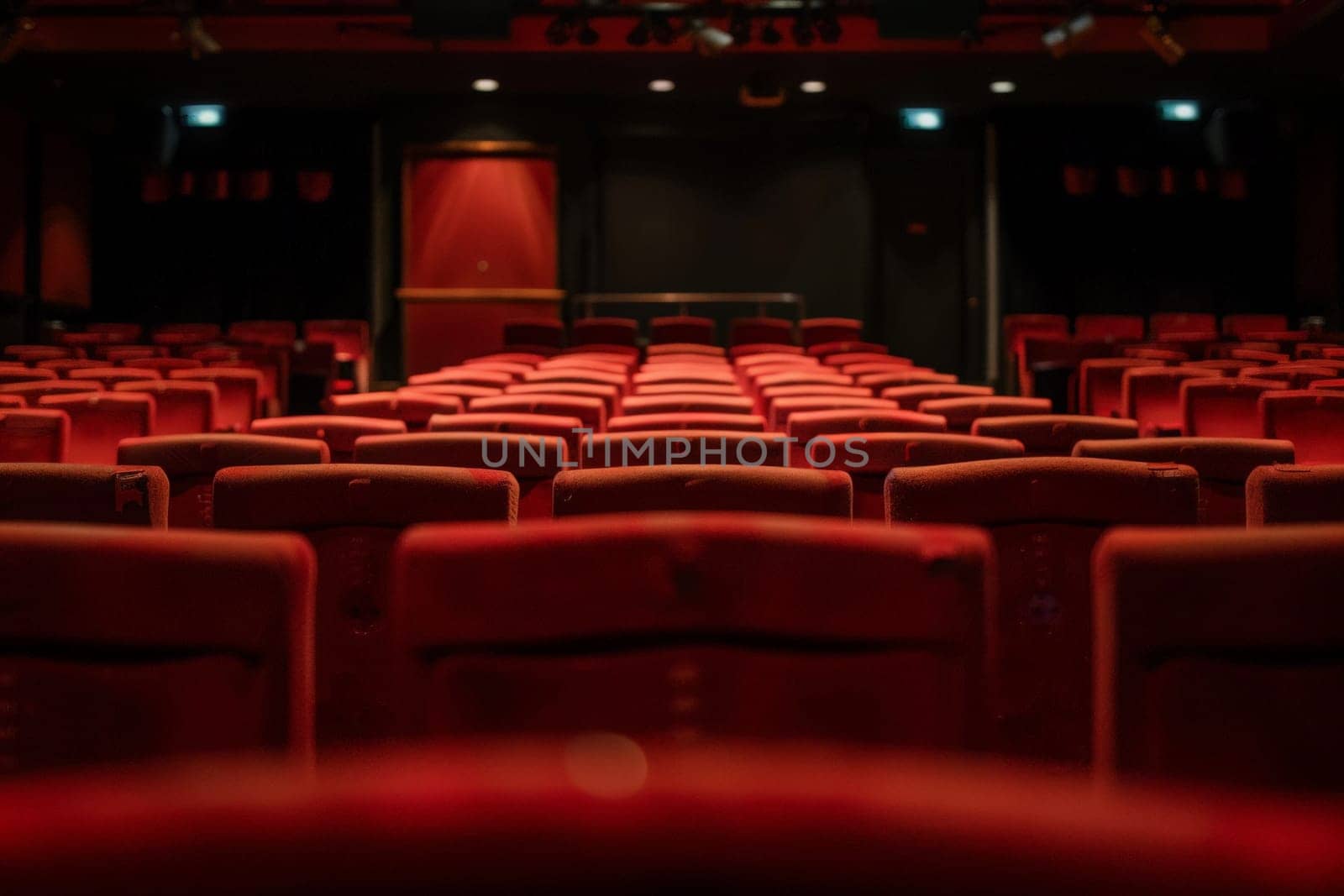 An empty theater with red seats and a projector screen, awaiting an audience for a captivating presentation.