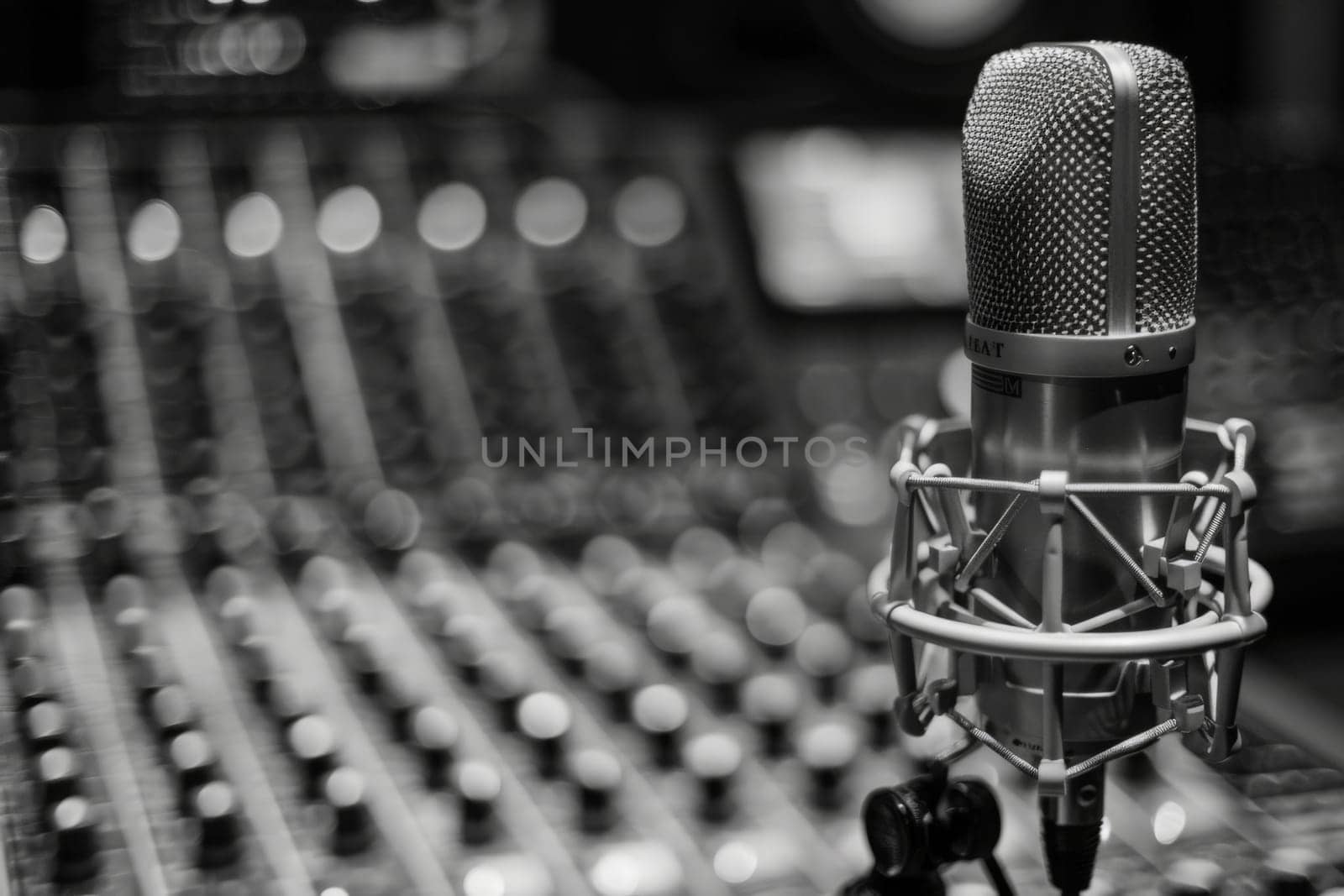 A microphone poised in front of a sound board, ready to capture and enhance the intricate harmonies and tones of the audio being produced.