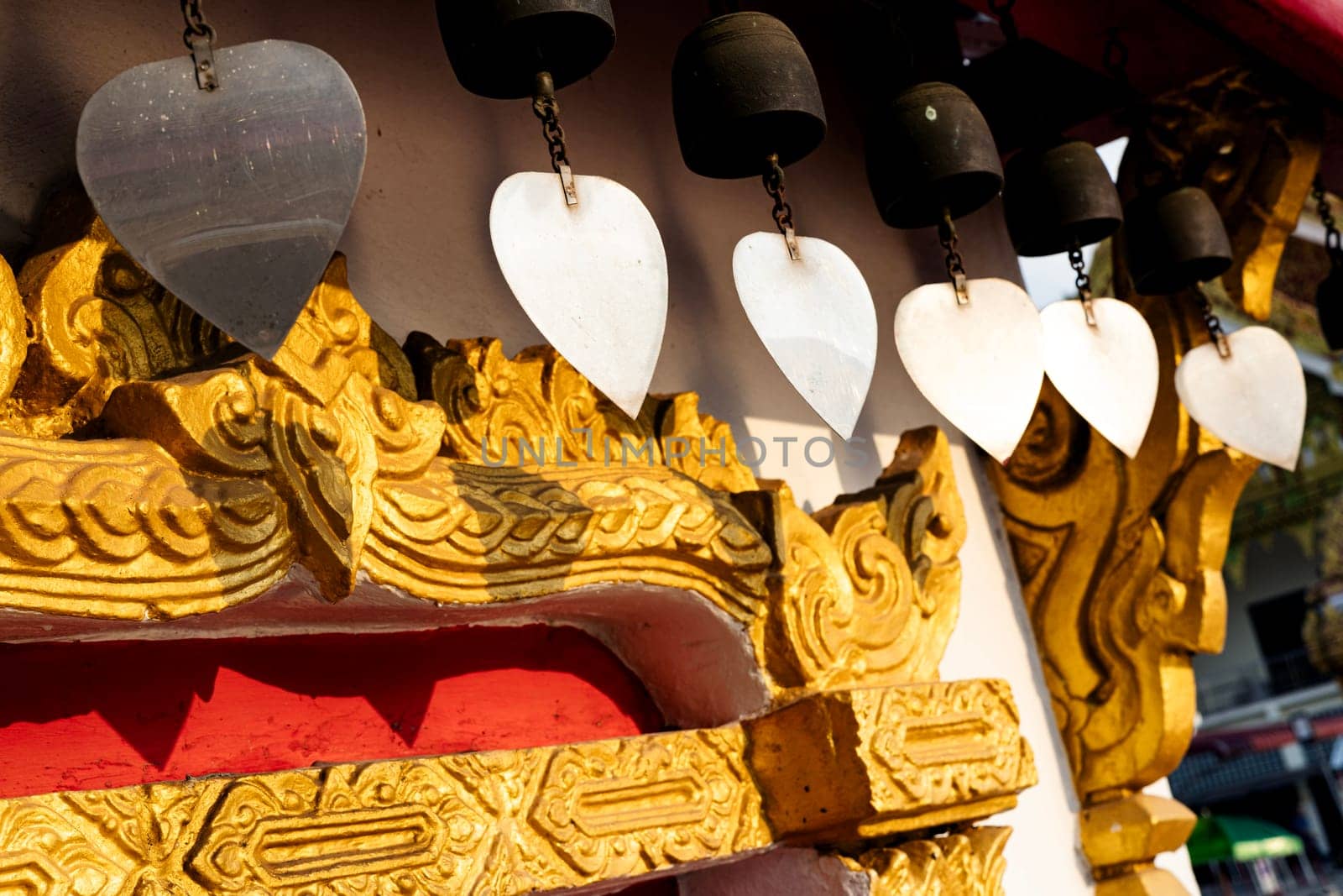 A row of bells hanging from a building. The bells are hanging from a wooden roof structure.