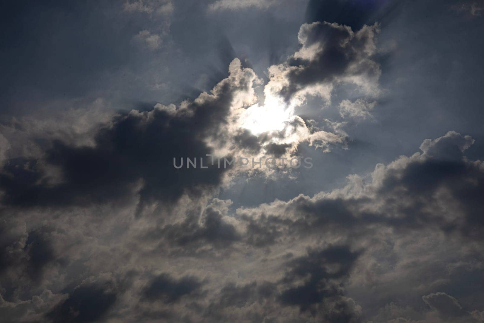 Cloudscape of sky with heavy rain backdrop. The bright sun behind the thick clouds