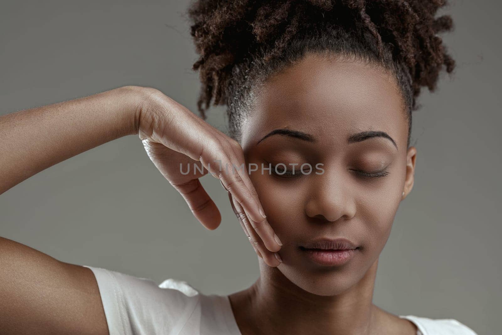 Serene young black woman with closed eyes, hand gently touching face