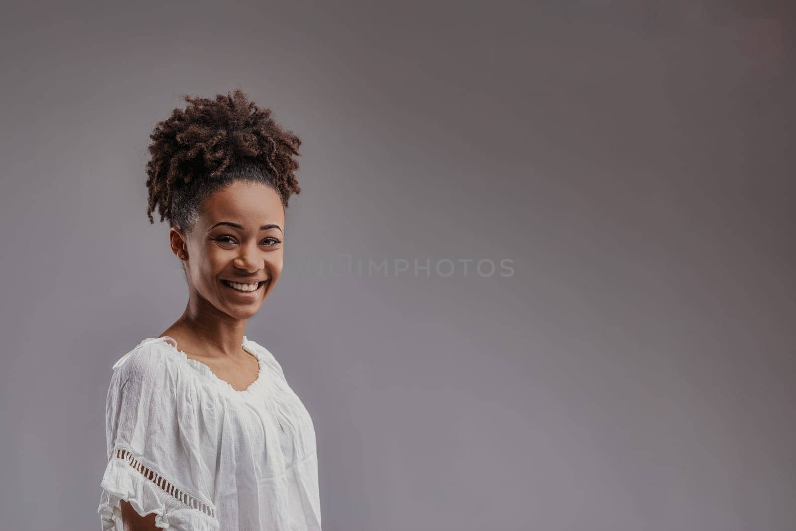 Radiant and carefree, the young womans smile is framed by her casual, bohemian-style white top near COPYSPACE