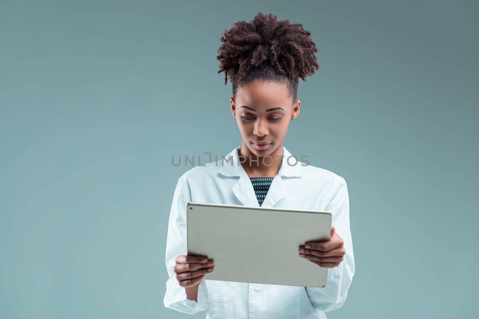 Professional young woman attentively examines a tablet, her intelligent gaze absorbed in the screen content