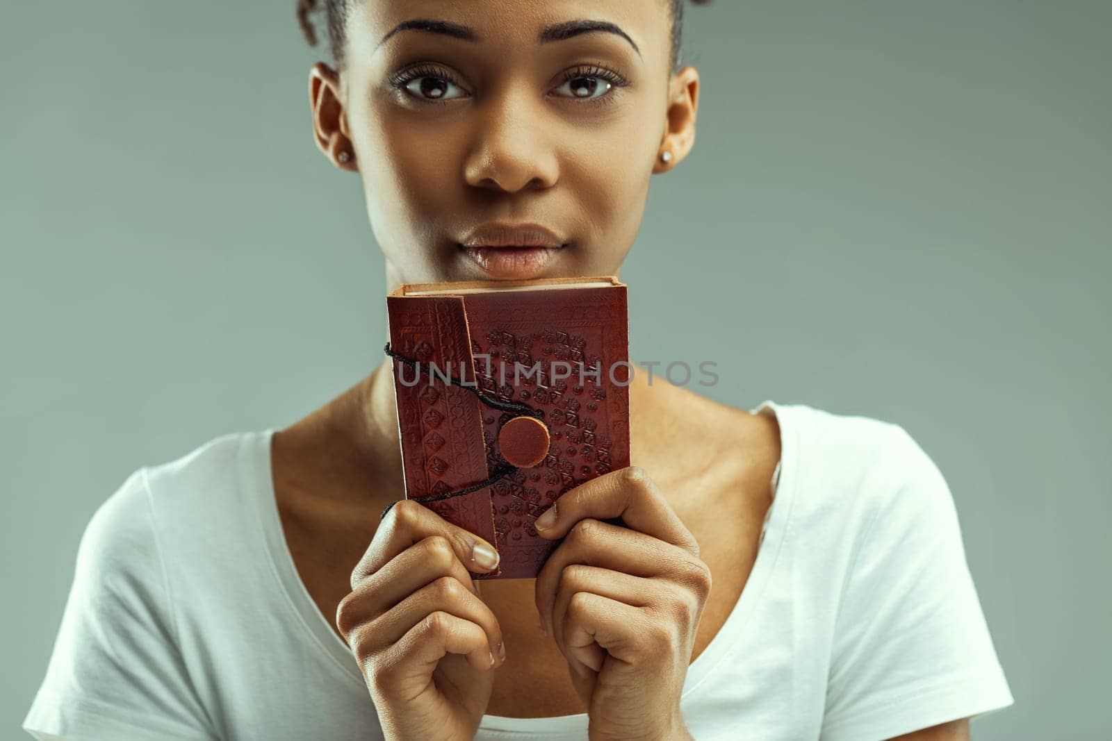 Eyes full of stories, a young woman gazes over a vintage red book, mystery abounds