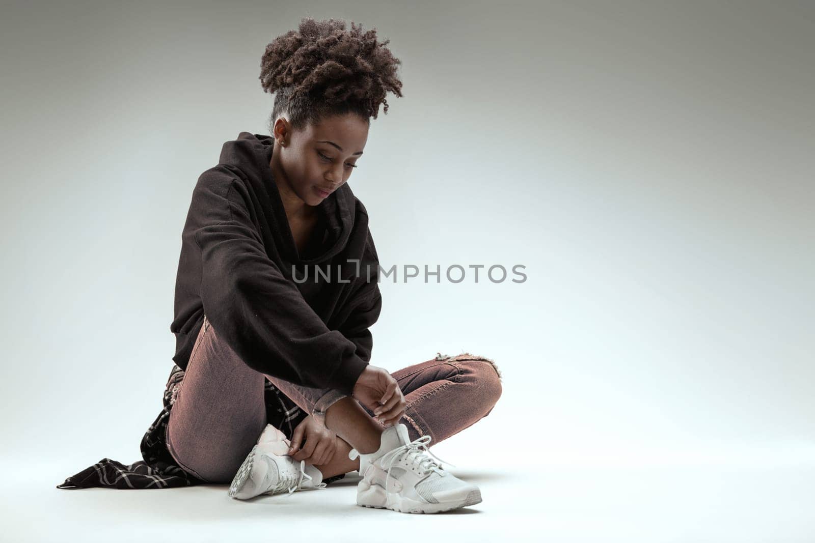 Relaxed young woman with a gentle look sits comfortably in jeans and hoodie