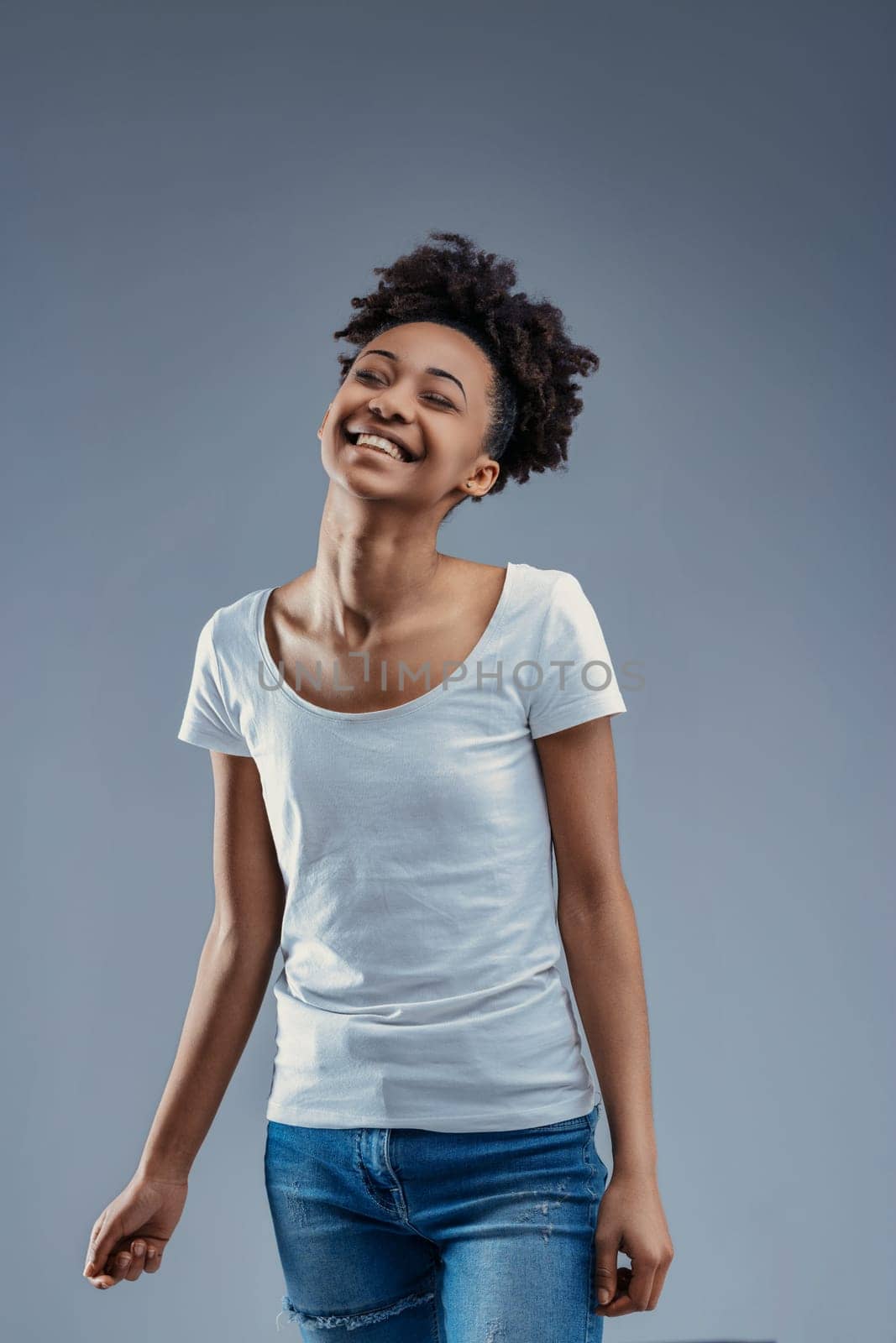 Delightful young woman enjoys a light moment, her afro and casual style epitomizing relaxed joy