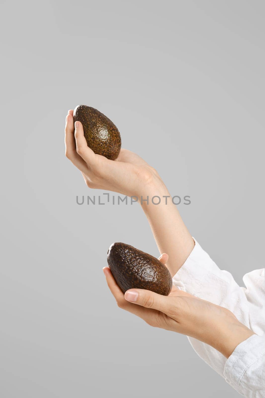 Female hands hold two whole avocado