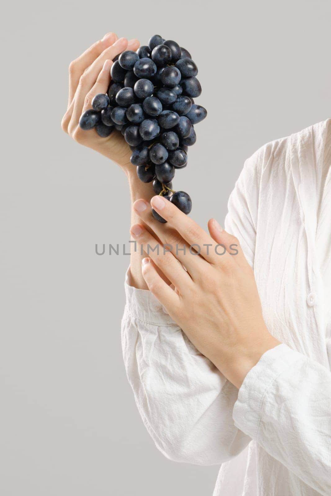 Unrecognizable woman holds a bunch of ripe grapes in her hand