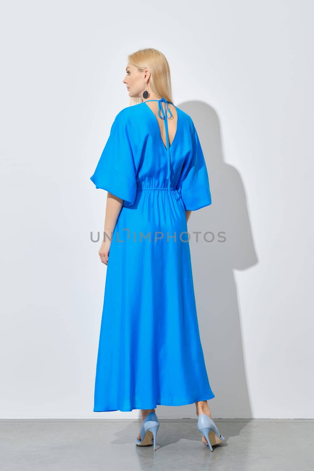 Back view of blonde woman in vibrant long blue dress