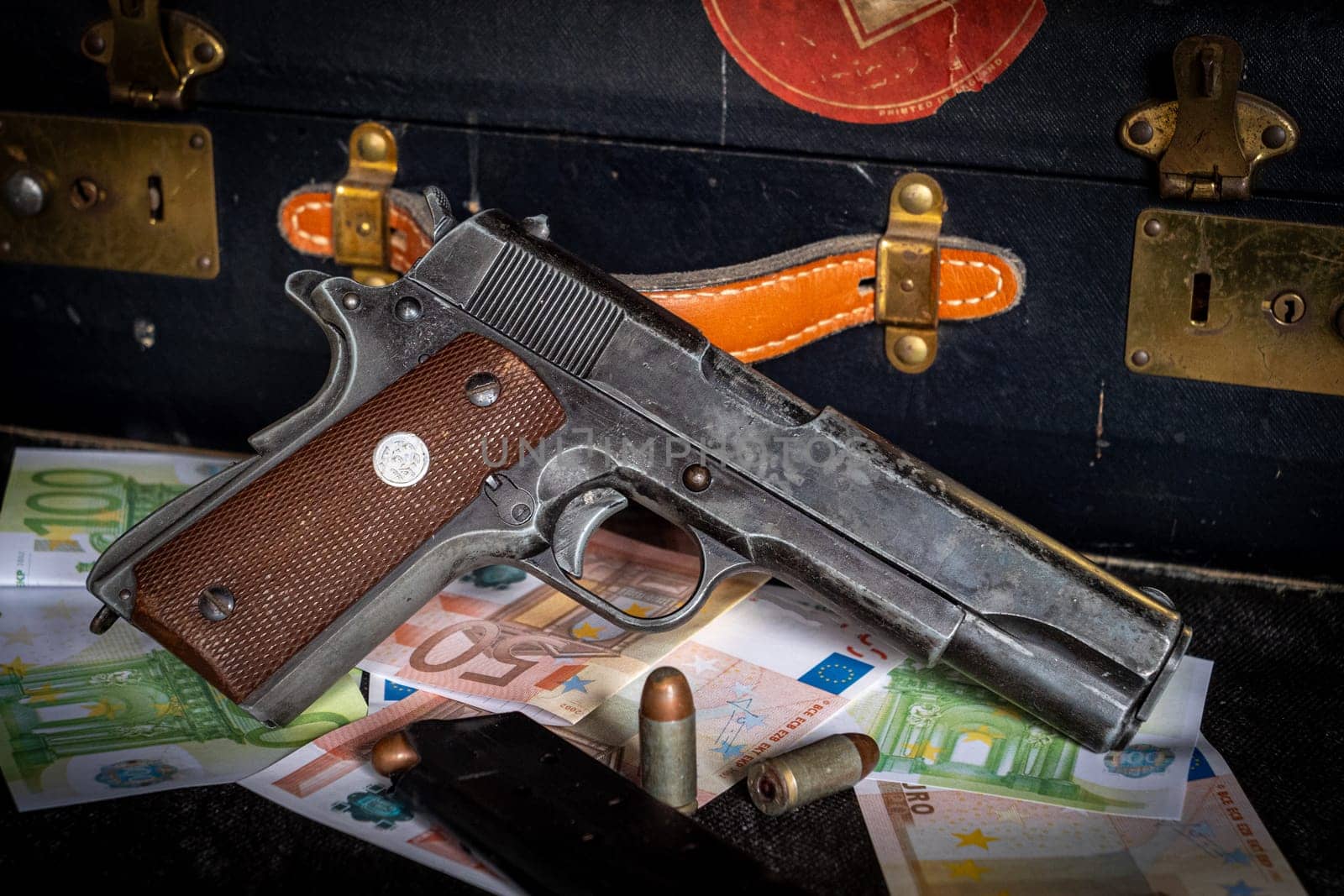 a close up of colt 1911, ammos and money, suitcase on background
