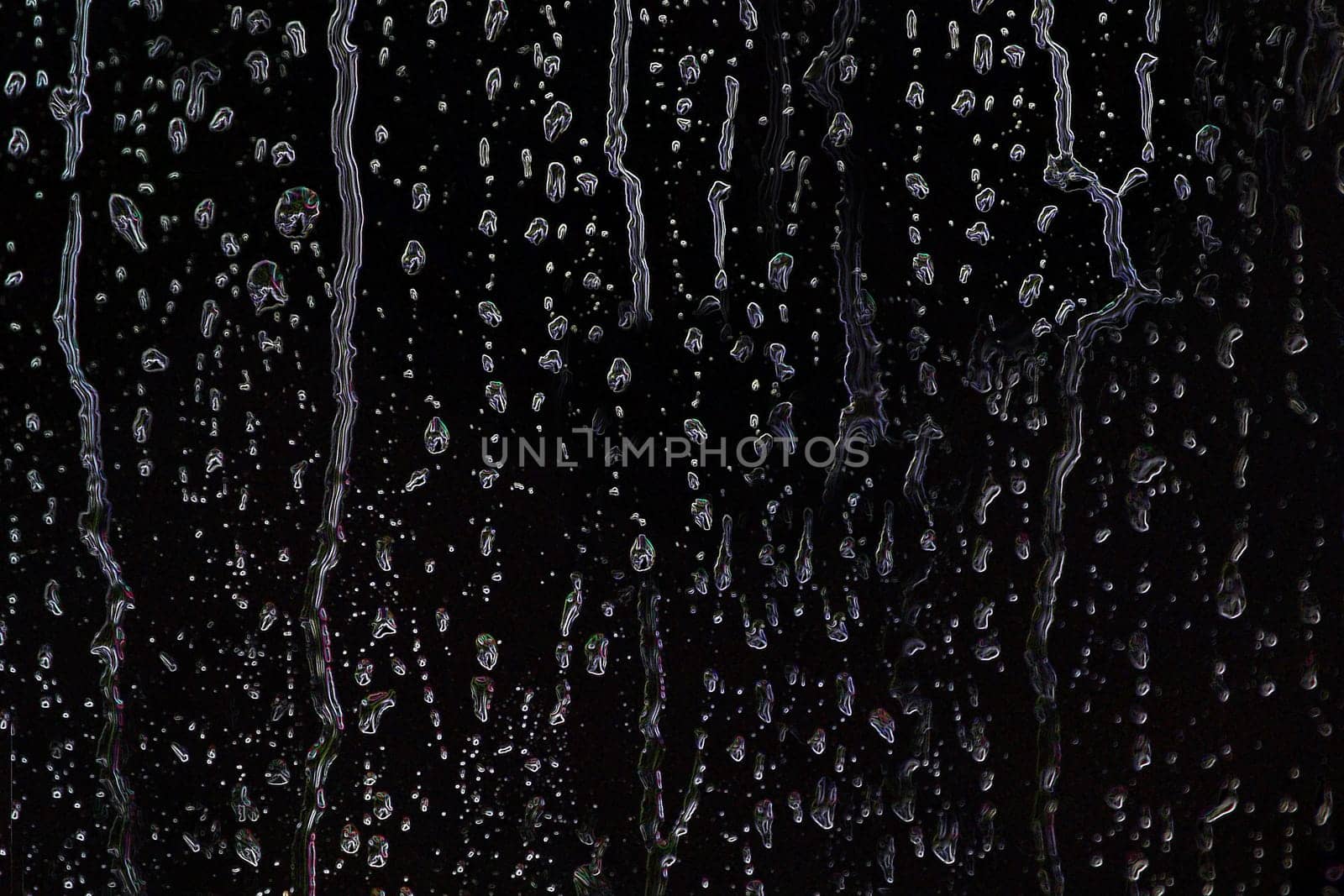 Drops of water or rain spread over a black background in close-up