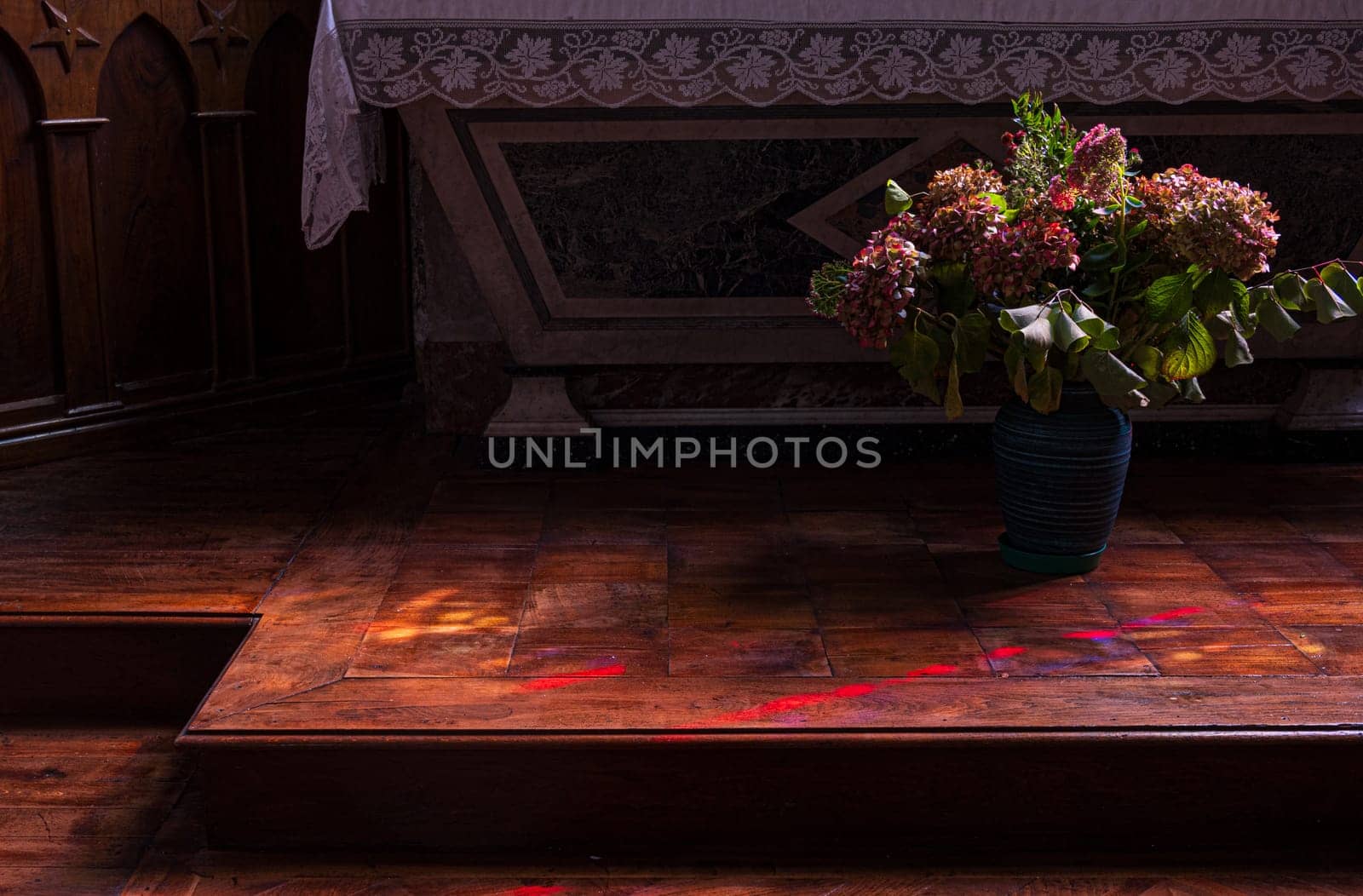 Flowers at the foot of the church altar. Dark atmosphere of contemplation. Photography taken in France