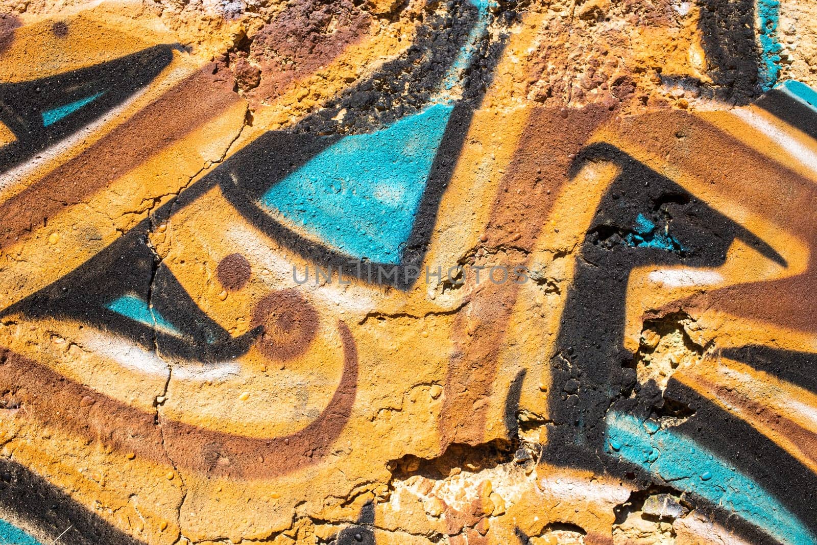 Detail of ocher and turquoise colors graffiti painted on the wall of a ruin, photogaphed in Portugal