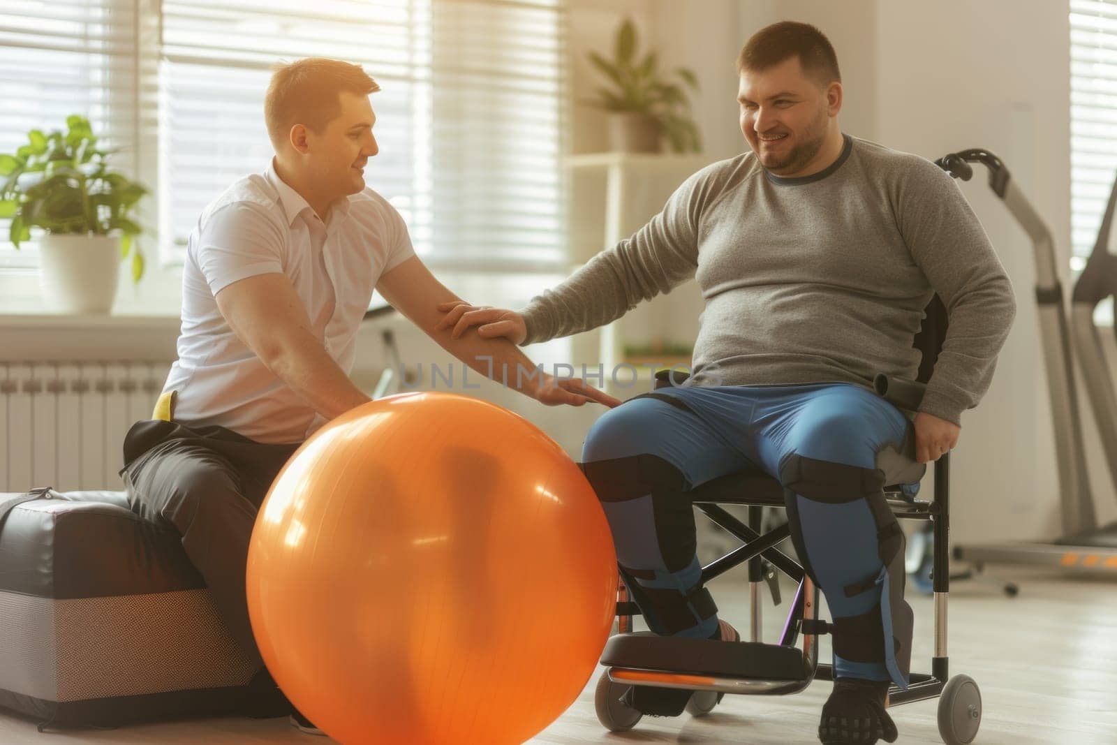 Physical therapist motivates a male patient with a gym ball during rehabilitation to improve his mood